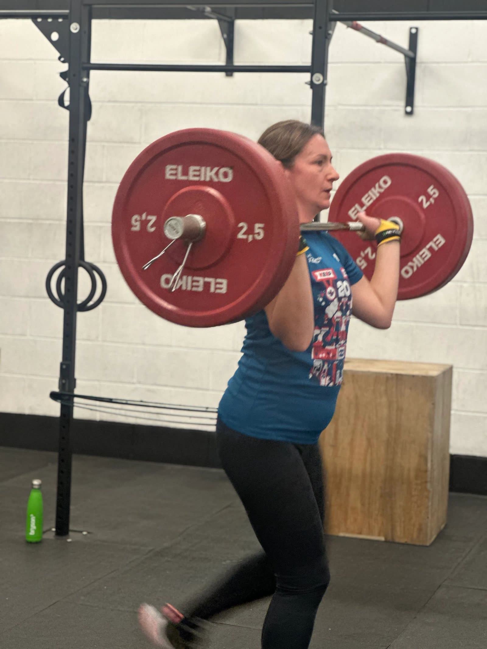A member lunging with a barbell across her shoulders in the gym