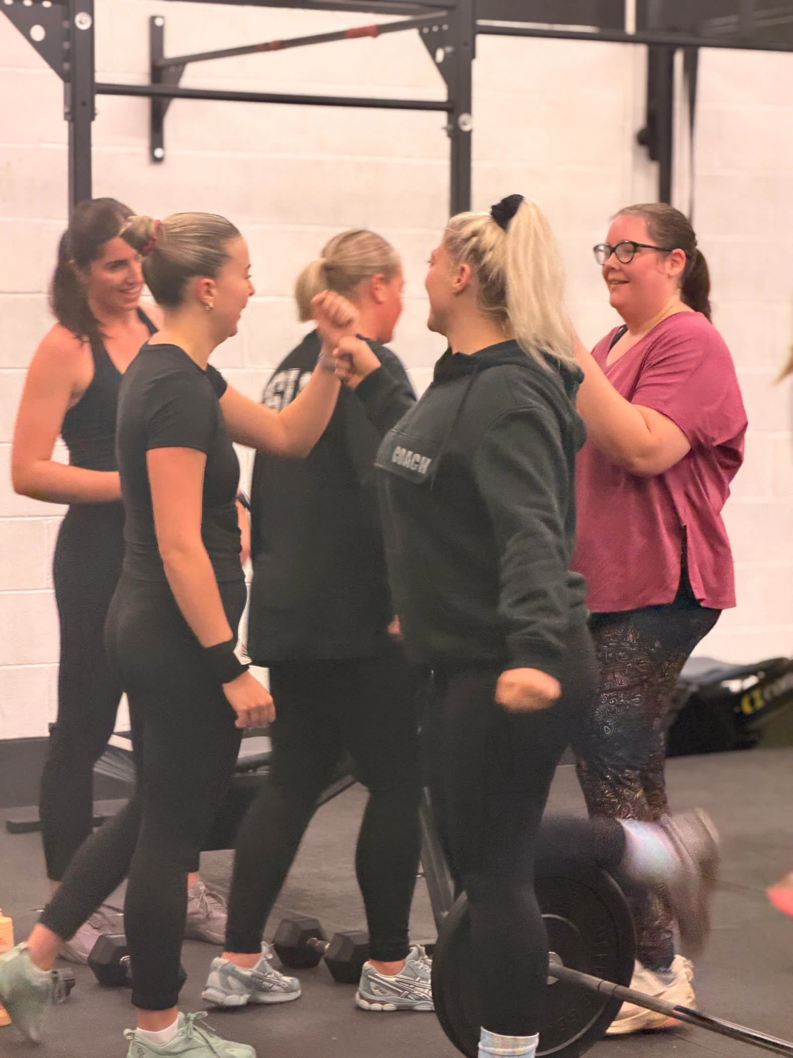 A group of women laughing together in the gym after a workout