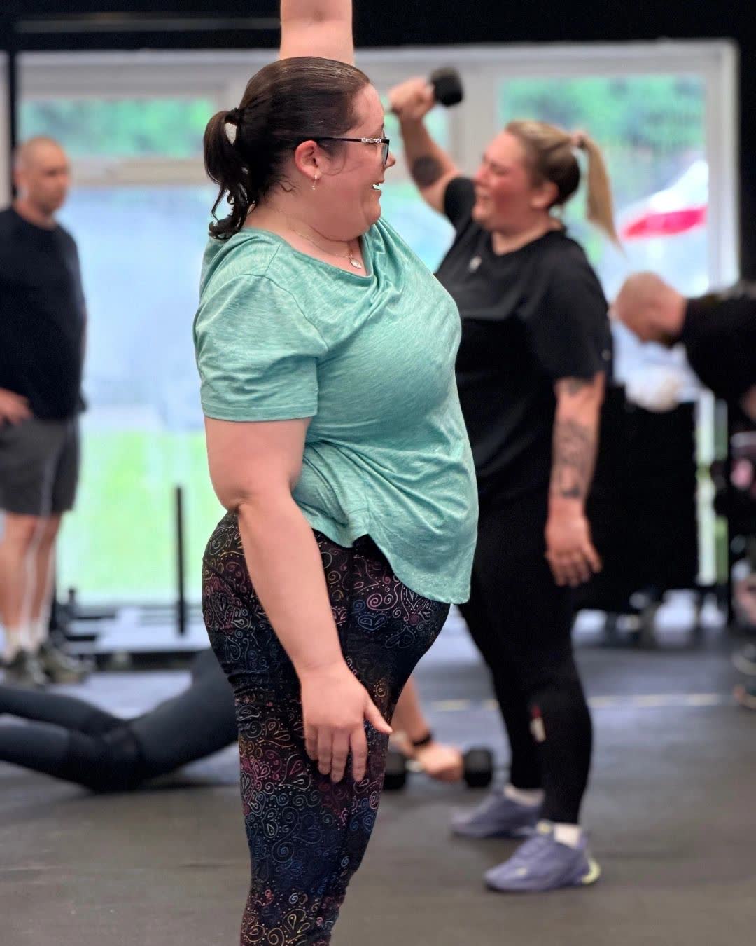 Two women laughing together on the gym floor during a class