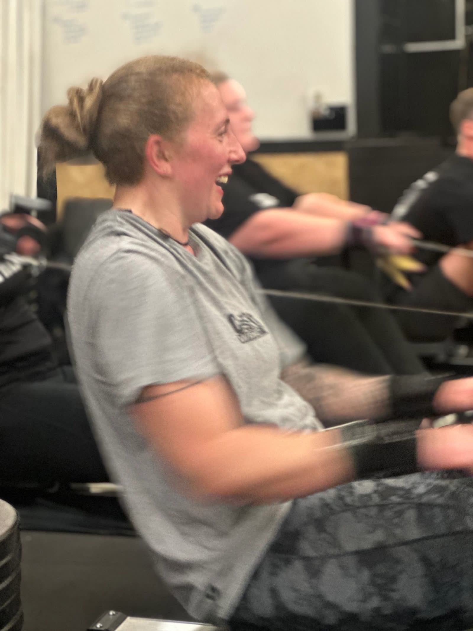 A smiling member pulling hard on a rowing machine