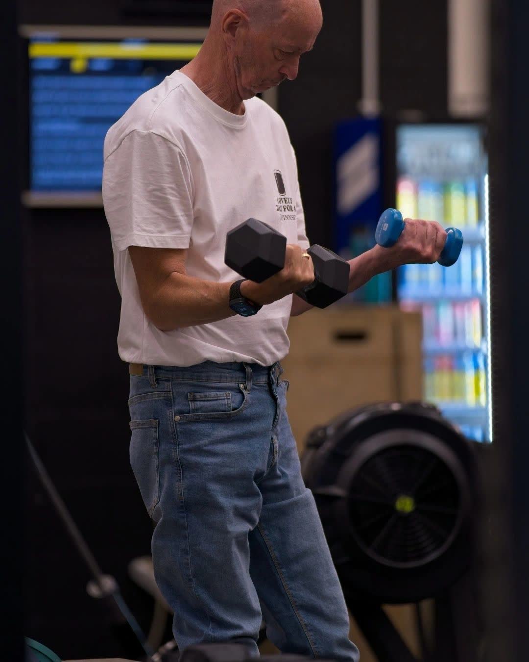 An older member doing dumbbell curls in the gym