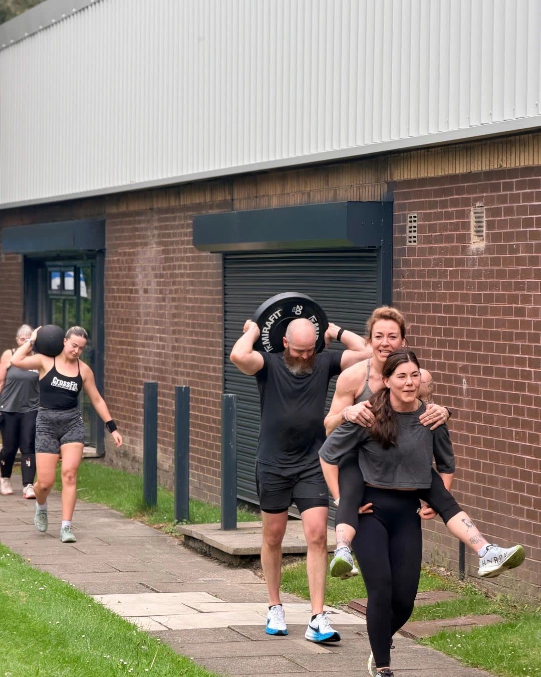 Members carrying weights along the path outside the gym