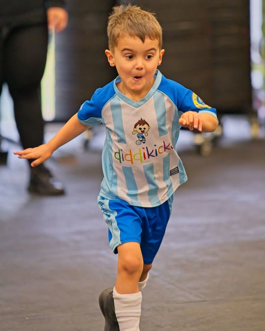 A young boy running with a big smile in the gym