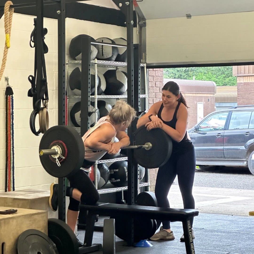 Two athletes working at a barbell rack