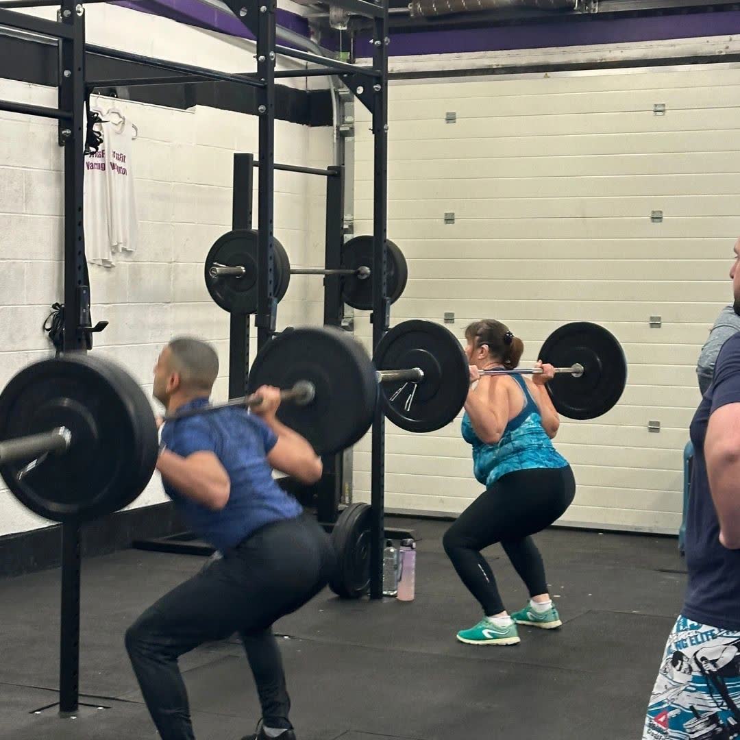 Two athletes back squatting side by side