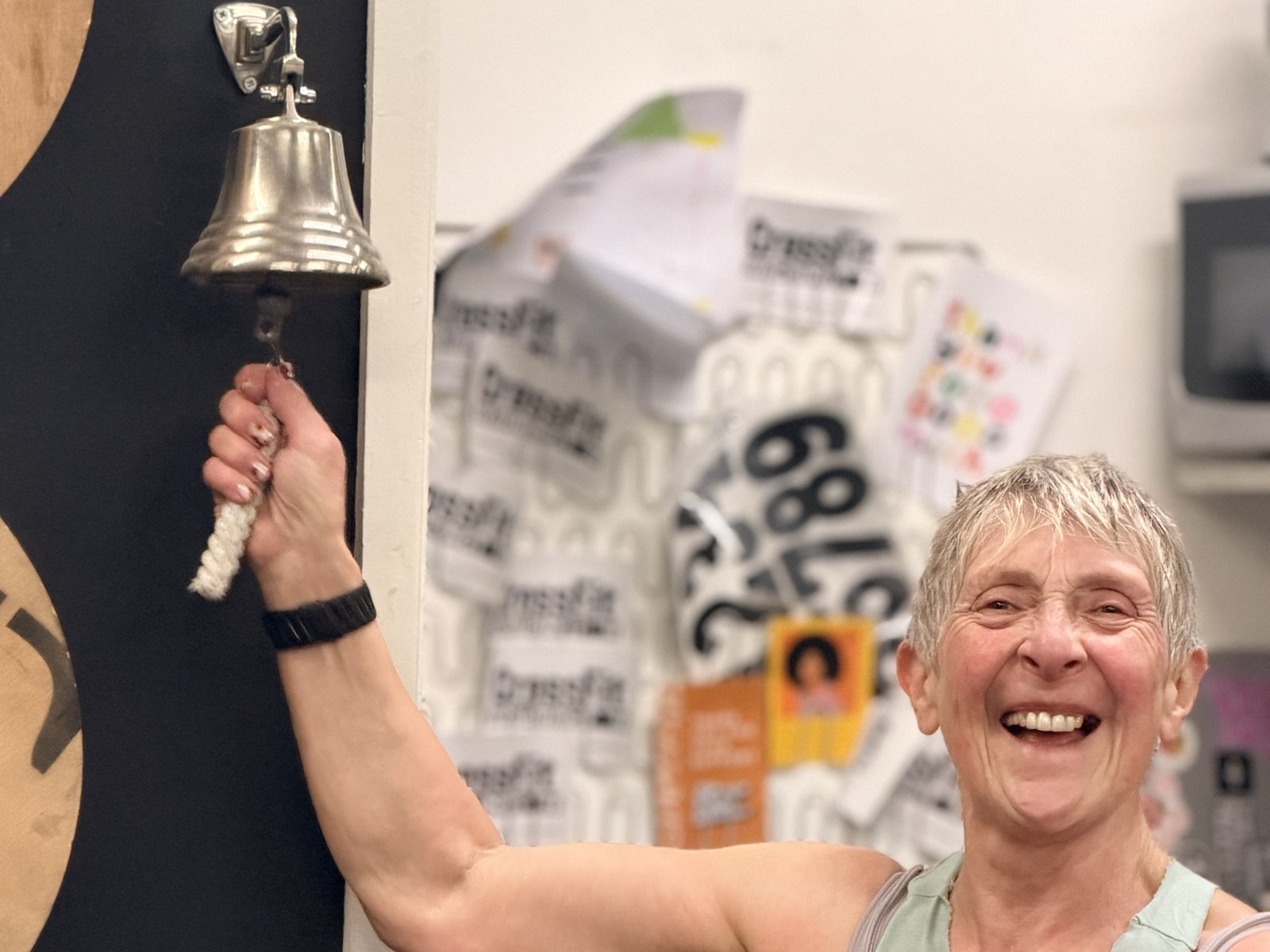 Carol smiling and ringing the PB bell at CrossFit Warrington after a new squat personal best