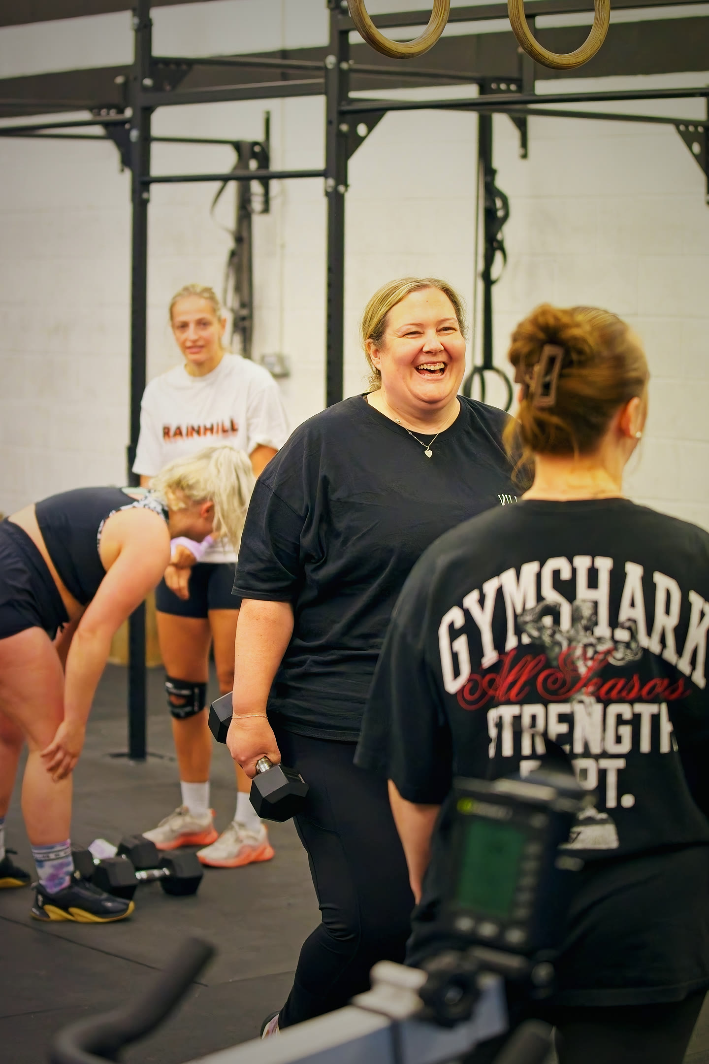 A Couch to CrossFit member laughing with her coach mid-session