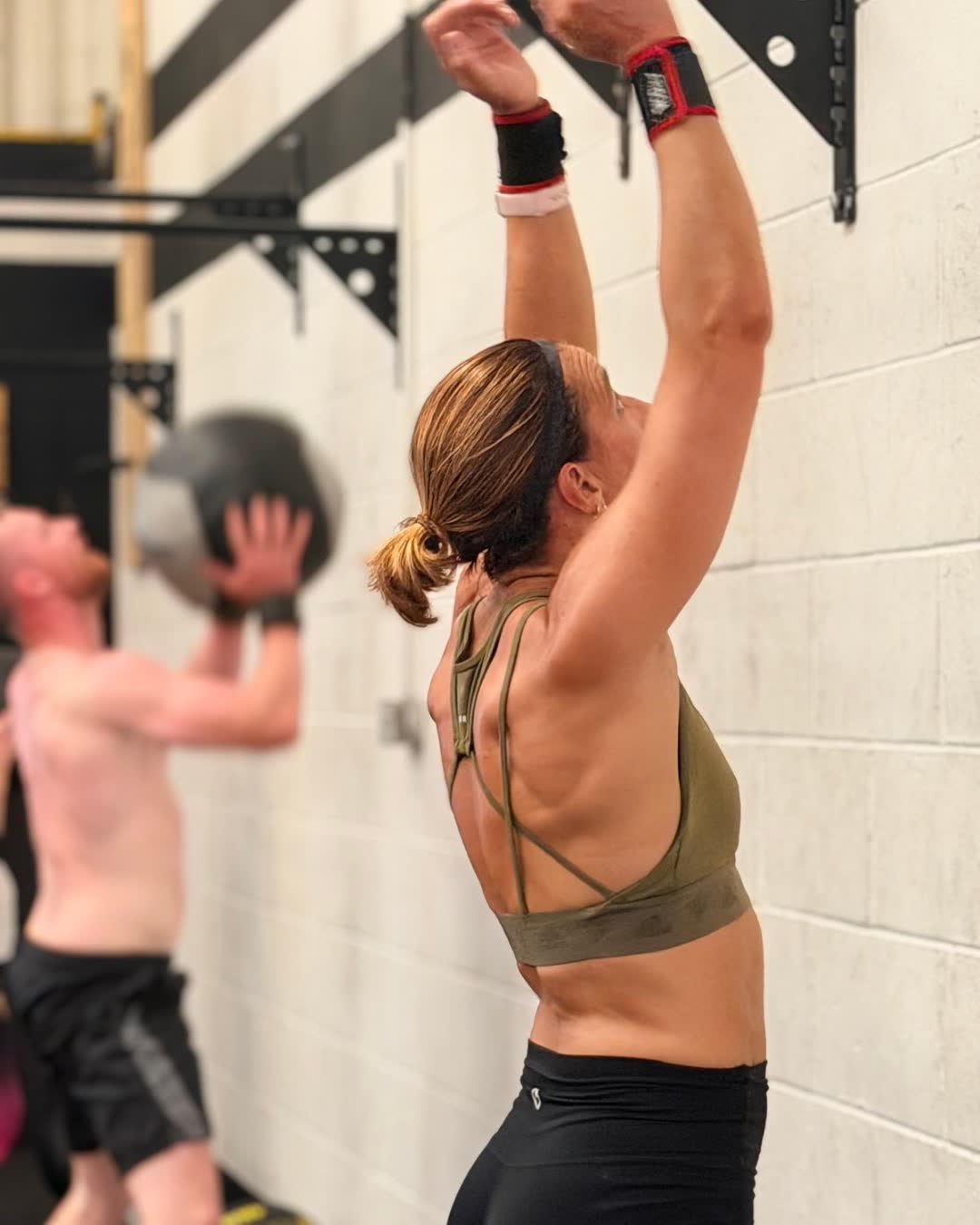 Two members throwing medicine balls up at a wall target