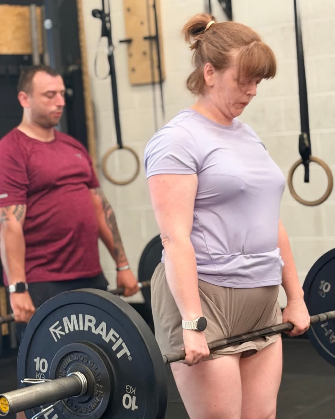 Two members lifting barbells during a class